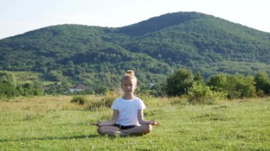 Lotus poz oturan ve meditasyon küçük kız. üzerinde yeşil bir glade.