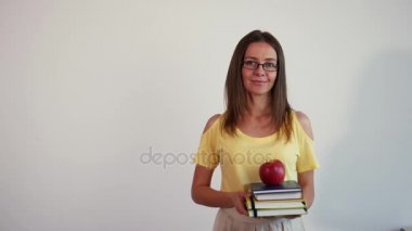 Beyaz arka plan üzerinde genç öğretmen portresi. Kitaplar ve elma üst yığını ile kız. 