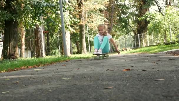 Junges Mädchen fährt das Skateboard sitzend im Park. Zeitlupe. — Stockvideo