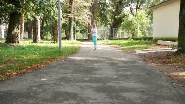 Çocuk ustaca parkta kaymaktadır. bir kaykay üzerinde 7-8 yaşında kız. Ağır çekim — Stok video