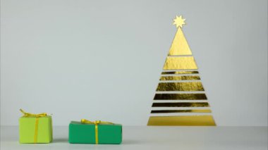Hediyeler bir dizi çerçeve içine gider ve ağacın altına yerleştirilir. Noel hediyeleri olan altın yeşil renkteki ağacın altında. Stop motion