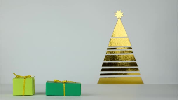Uma série de presentes entra no quadro e é colocada sob a árvore. Presentes de Natal sob a árvore em esquema de cor verde dourado. Parar movimento — Vídeo de Stock