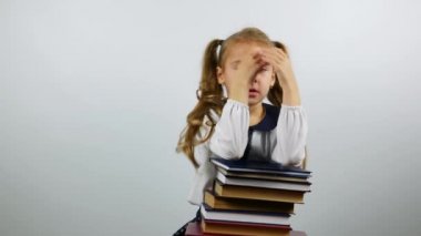 Beyaz zemin üzerinde bir kız öğrenci öğrenme yorgun. Bir yığın kitap ve görünüyor yorgun tutan kız.