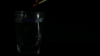 Yanan bir sopayla sambuca ateşleme. Siyah bir arka plan üzerine açık alkol bir bardak. 