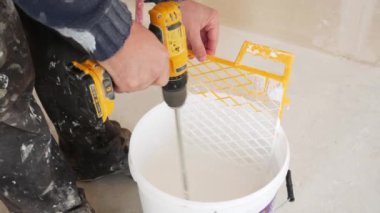 İşçi elektrikli matkap ile boya bir kova içinde karışımları