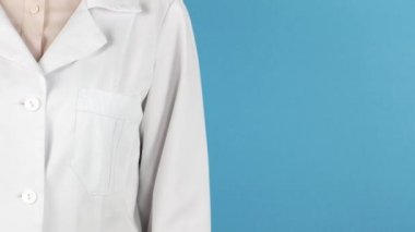 Mavi arka planda steteskop tutan kimliği belirsiz genç bir kadın doktor portresi. Steteskopla doktorun ellerini kapatın..
