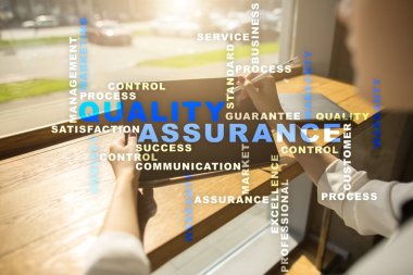 Kalite güvencesi kavramı sanal ekran üzerinde. İş kavramı. Kelime bulutu