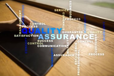 Kalite güvencesi kavramı sanal ekran üzerinde. İş kavramı. Kelime bulutu.