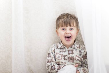 Kameraya bakarak beyaz perdeler yakınındaki küçük çocuk 