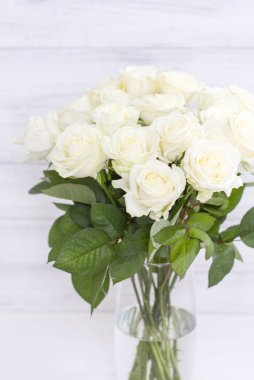 Cam vazo içinde sunulan yaprakları ile şık beyaz gül buketi.