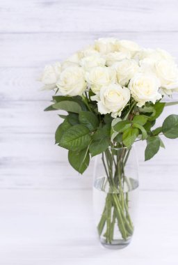 Cam vazo içinde sunulan yaprakları ile şık beyaz gül buketi.