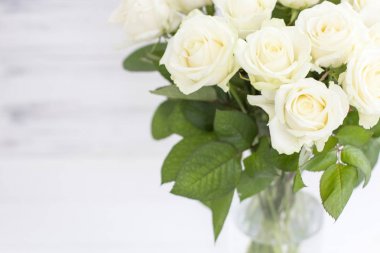 Cam vazo içinde sunulan yaprakları ile şık beyaz gül buketi.