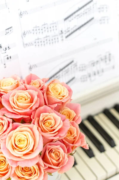 Beautiful pink roses in a round box on the piano.