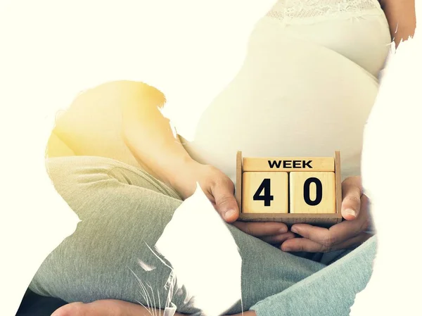 Podwójnej ekspozycji młody mężczyzna całuje brzuch jego uroczej żony w ciąży i kalendarz 40 tygodni — Zdjęcie stockowe