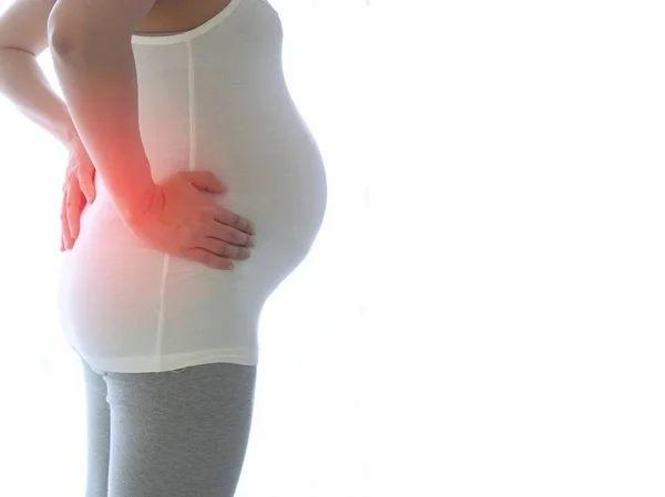 흰색 배경에 고립 된 허리 통증 임신 여자. 임신 건강 관리의 개념. 스톡 사진