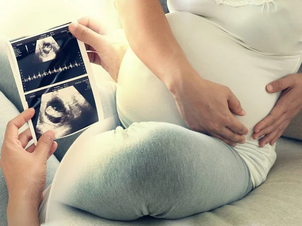 Gravid kvinna håll ultraljudsundersökning och har ont i magen. Begreppet graviditet vård. Stockfoto