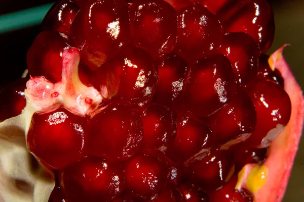 Red grains of ripe pomegranate are photographed closeup.