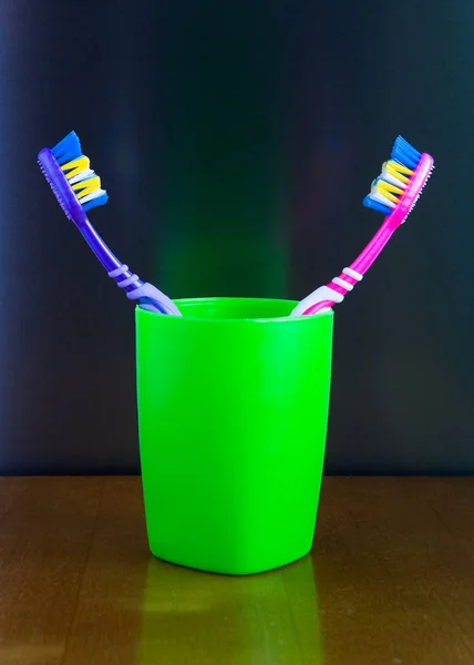 Zwei bunte Zahnbürsten stehen in einem Glas. — Stockfoto