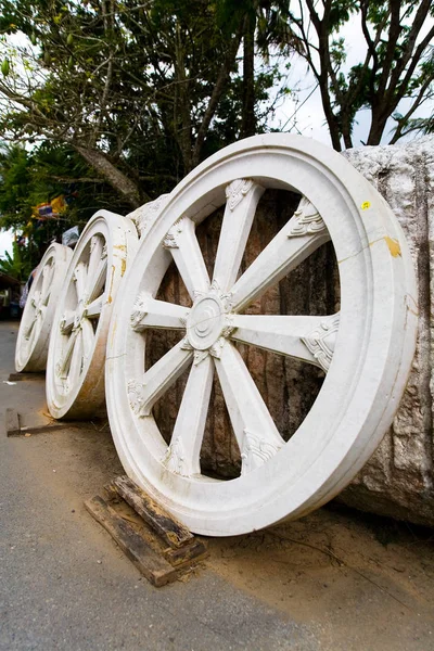 Три больших колеса из камня стоят напротив стены . — стоковое фото