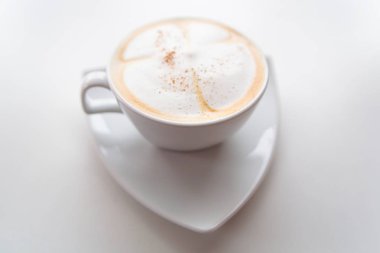 Beyaz bir daire üzerinde beyaz bir fincan kapuçino.