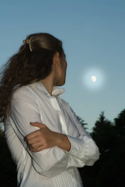 The long-haired blonde looks at the moon.