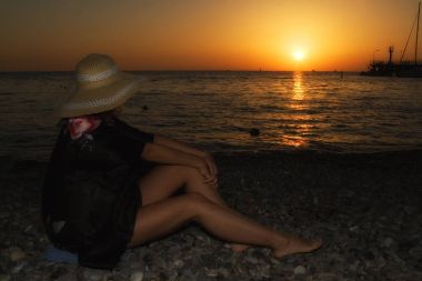 Güzel ince uzun bacakları su izlerken ile şapkalı bir kız