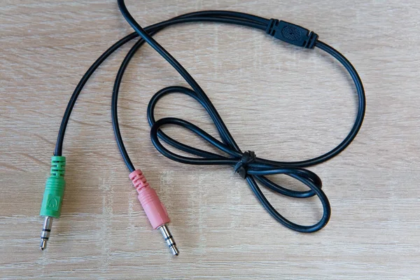 Kabely od sluchátek se dvěma konektory leží na dřevěné bac — Stock fotografie