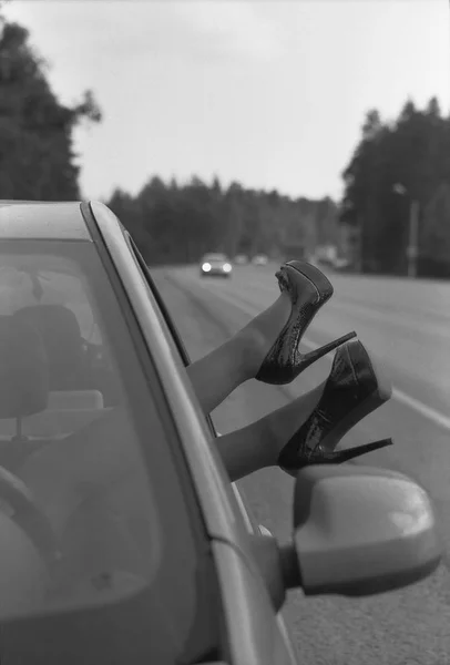 Ženské nohy v botách na vysokém podpatku držet mimo auto. — Stock fotografie