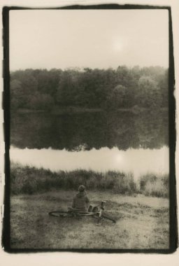 Bir kız bir gölet yakınındaki bir bisiklet ile.