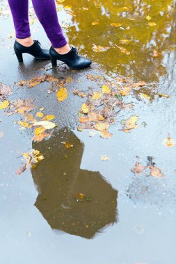 Bir adam bir şemsiye ile bir su birikintisine yansıtılır.