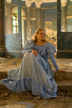 Merdivenlerde bir ortaçağ elbiseli bir kız oturuyor. 