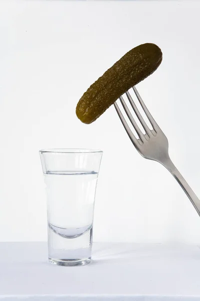 Concombre sur une fourchette et un verre de vodka . — Photo