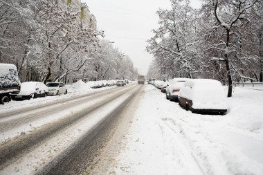Yol ve park etmiş arabaların karla kaplı.