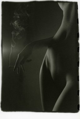 İnce, çıplak bir kadın sigara içiyor..