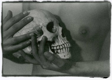 Zarif kadın elleri bir insan kafatasını çıplak dişi bir Brea 'ya bastırır.