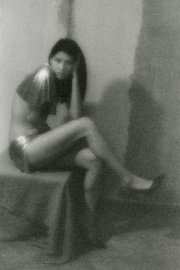 Güzel, yarı çıplak, ince bir esmer hırpalanmış bir vajinanın yanında oturuyor.