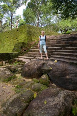 Cute natural barefoot blonde stands on the old steps.