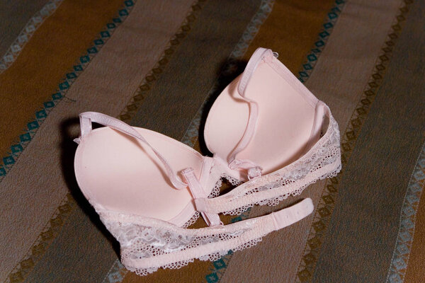 A female bra lies on the bedspread.