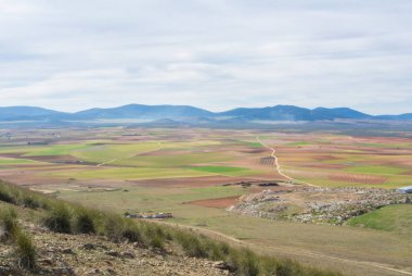 Bir tepeden bir görünüm alanları, çiftlikler ve dağlarına bahar bulutlu gün Consuegra town yakınındaki.