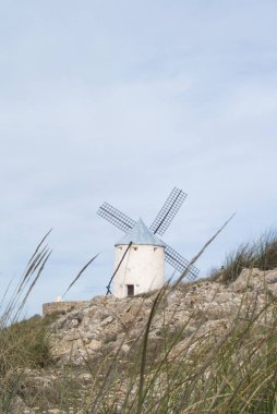 Beyaz eski yel değirmeni Consuegra (Castilla La Mancha, İspanya), yakınlarındaki tepe üzerinde bölge sembolü ve Don Kişot (Alonso Quijano) seyahat bulutlu gün.