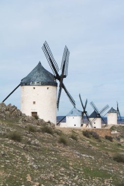 Beyaz eski Consuegra (Castilla La Mancha, İspanya), yakınlarındaki tepe üzerinde bölge sembolü ve Don Kişot (Alonso Quijano) seyahat bulutlu gün yel değirmenleri.