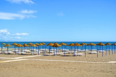 Yaz tatil görünümü bir turizm sezonu, kumlu bir plaj mavi deniz, şezlonglar, hasır şemsiyeler ve ahşap bir yol Torremolinos Resort Costa del Sol, İspanya için hazırlanan bir Akdeniz Beach.