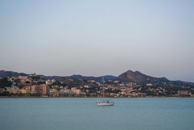 Şehir ve dağ arka plan, Meditarrain denizde akşam Malaga, Endülüs, İspanya yakınındaki bir yalnız tekne balıkçılık.