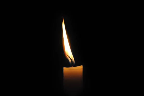 Close-up de uma vela acesa em um fundo preto . — Fotografia de Stock
