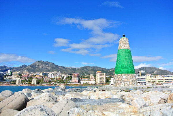 Вид на Средиземное море, маяк с волнорезом и отели на заднем плане с пирса в порту Бенальмадена Пуэрто-Марина, Андалусия, Испания
.