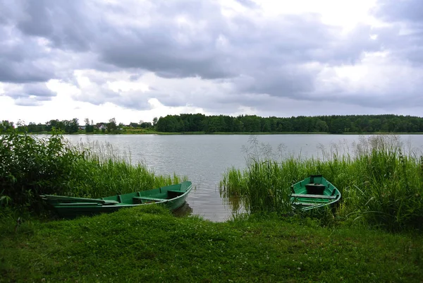 Regnvejrsdag i Trakai naturpark, udsigt til en sø, skov og grønne fiskerbåde, Litauen . - Stock-foto