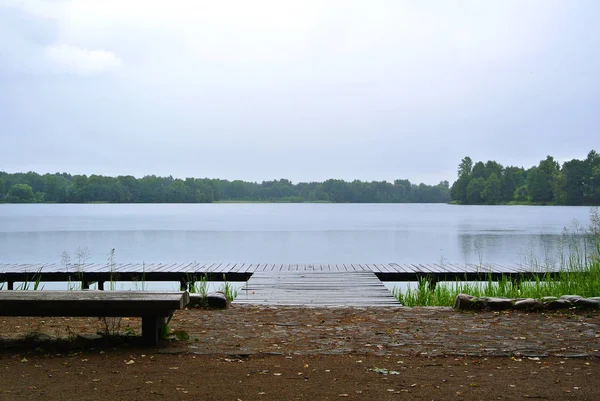 Βροχερή μέρα στο φυσικό πάρκο Trakai, μια προβολή σε μια λίμνη, δάσος, ξύλινο πάγκο και ξύλινη αποβάθρα, Λιθουανία. — Φωτογραφία Αρχείου