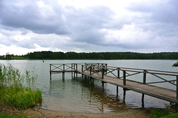 Hari hujan di taman alam Trakai, pemandangan danau, hutan, bangku kayu dan dermaga kayu, Lithuania . — Stok Foto