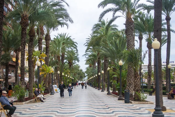 Alicante, Spanje - 12 februari 2016: Explanada de Espana, een beroemde promenade van Alicante, lantaarns, palmen en wandel- en ontspannen mensen, Alicante, Spanje. — Stockfoto