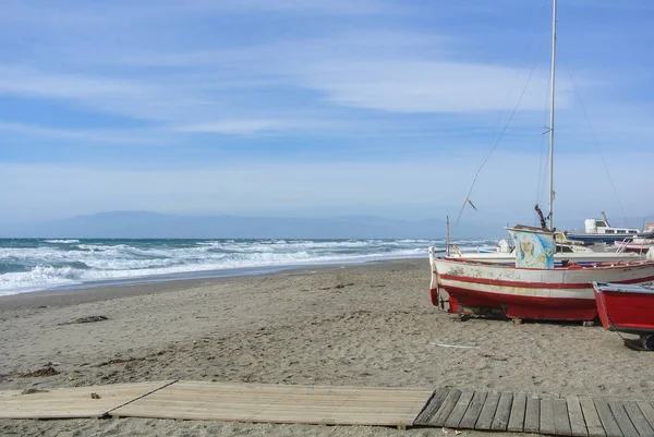 CABO DE GATA, ESPANHA - FEVEREIRO 9, 2016: Barcos de pesca na margem do parque nacional Cabo de Gata perto de Almeria (Andaluzia, Espanha) e ondas de mar ao fundo . — Fotografia de Stock